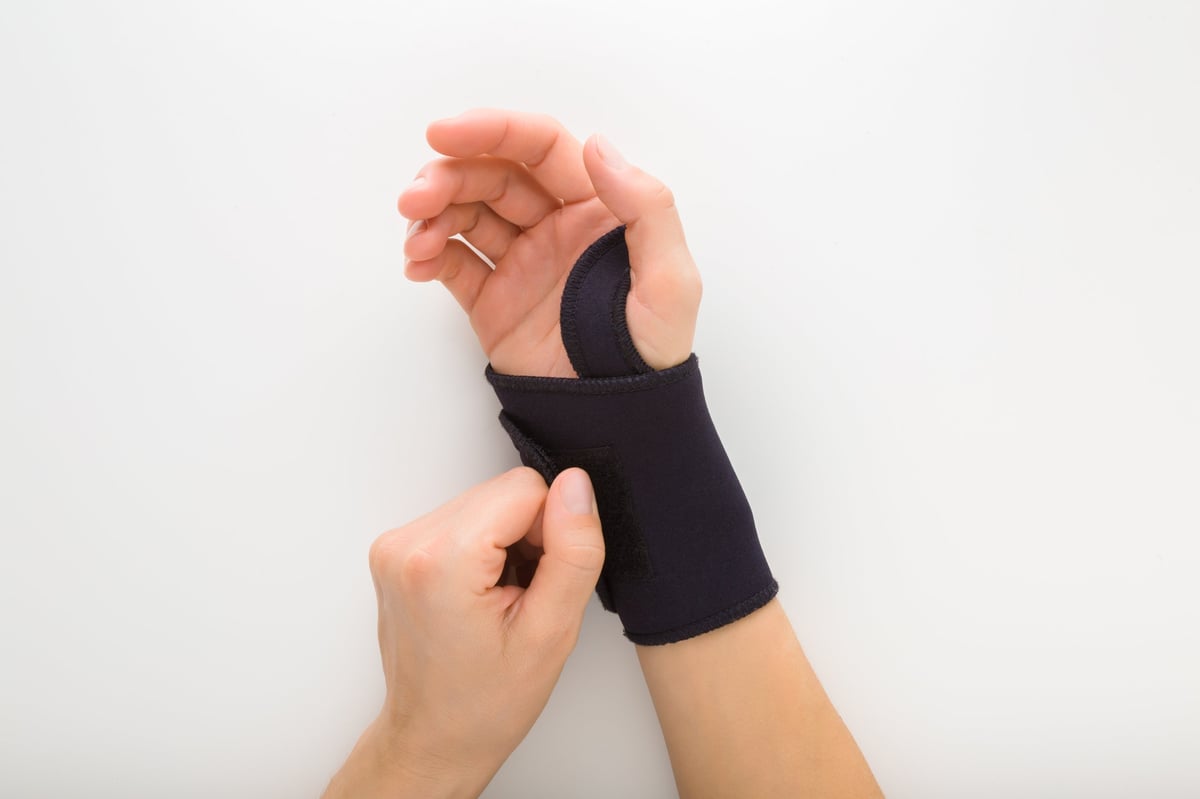 Close-up of a protective elastic wrist bandage being applied, the type worn to support a golfer's wrist