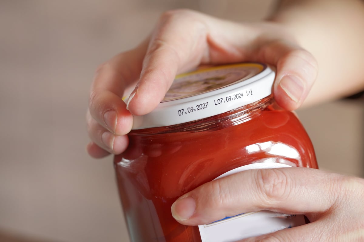 Woman using both hands to twist open a tightly closed jar lid