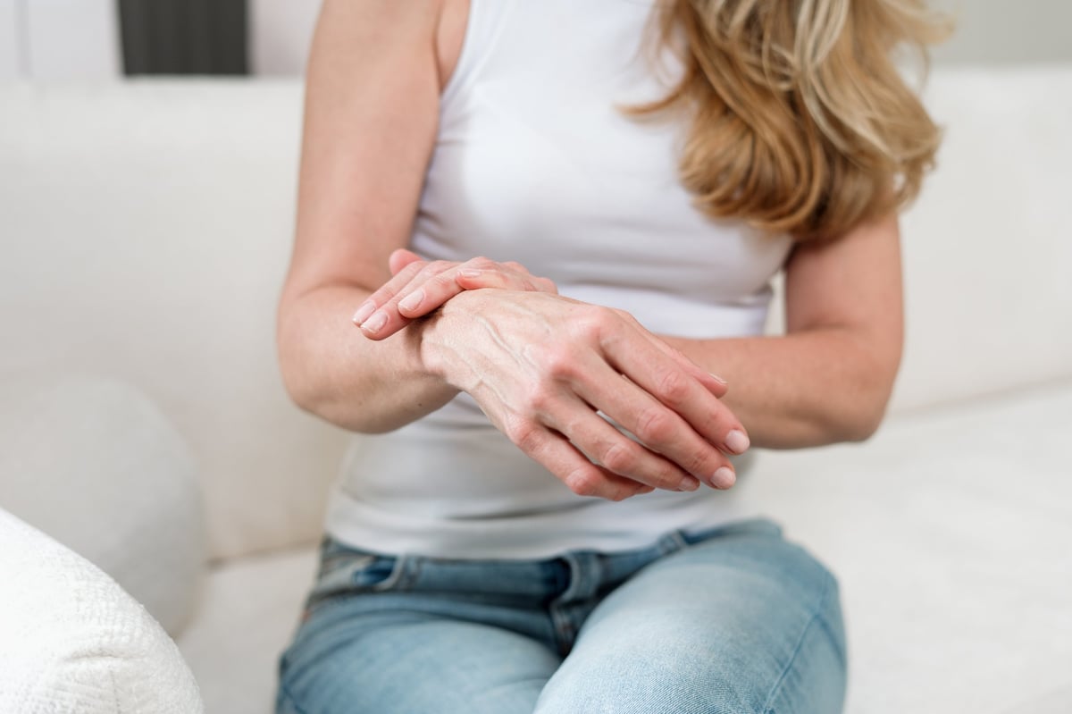 Person resting at home with wrist pain and stiffness, a common cause of nighttime hand numbness