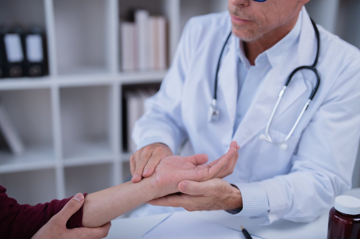 Orthopedic physician examining a patient's wrist and hand during an evaluation for carpal tunnel syndrome