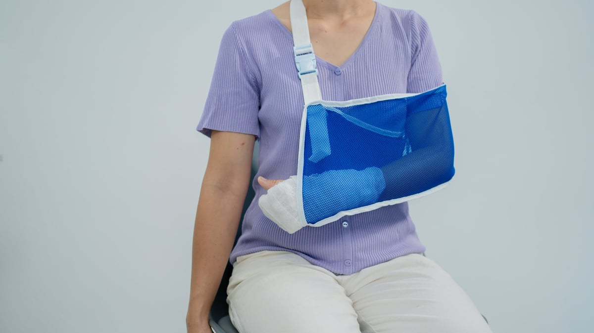 Patient supporting an injured arm in a sling, illustrating upper-extremity fracture care
