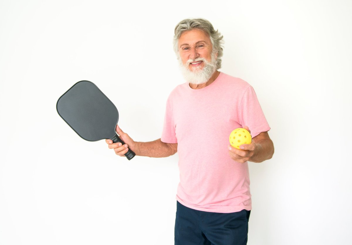 Adult pickleball player holding a paddle outdoors on the court