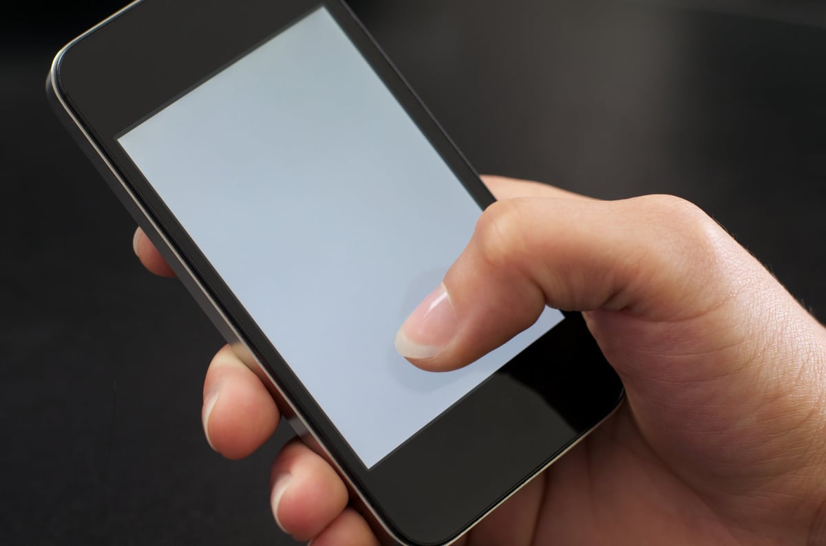 Hand holding a smartphone with the thumb extended toward the screen